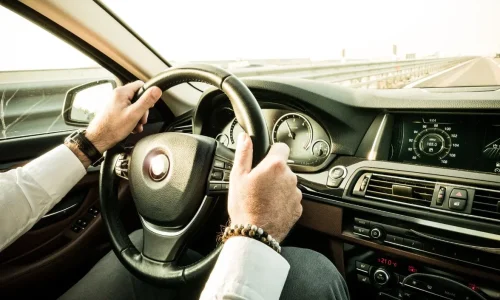 Mains sur volant dans habitacle moderne, image d’un trajet marqué par un bruit de ferraille