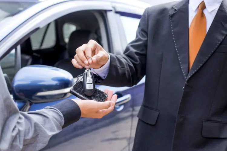 Remise de clé entre deux personnes en costume illustrant la finalisation d’un achat de voiture d’occasion avec carte grise barrée