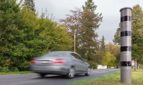 Voiture argentée floue devant radar fixe