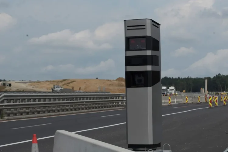 Radar tourelle gris et noir installé au bord d’une autoroute en construction, illustrant la surveillance routière et le contrôle des vitesses