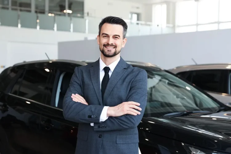 Personne en tenue formelle debout devant véhicule noir, reflétant le contexte d’achat d’une voiture professionnelle pour usage business.