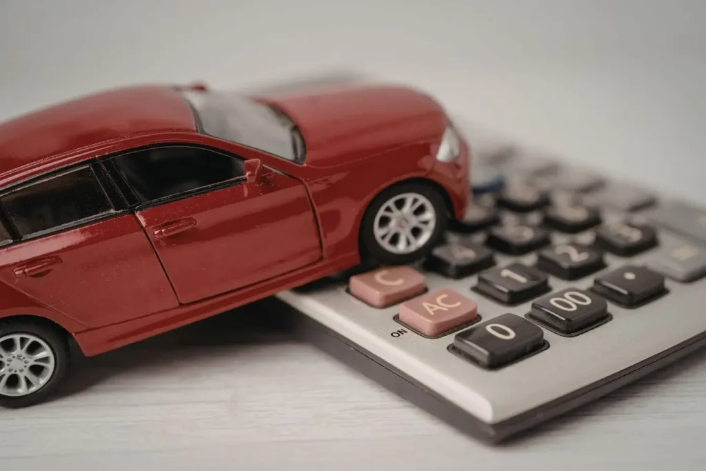Voiture rouge miniature posée sur calculatrice, incarnant le calcul des mensualités et taux d’intérêt liés au crédit auto