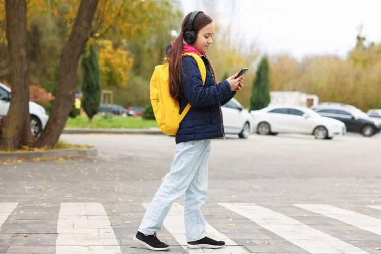 Jeune en veste bleue et sac jaune marche sur passage, image inspirant le stage de sensibilisation sécurité routière obligatoire