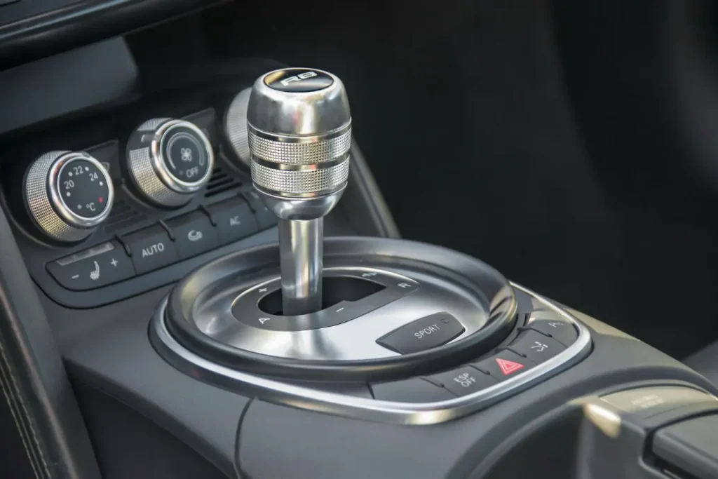 Levier de vitesse marqué R8 entouré de commandes sport, image représentant la boîte de vitesses DSG et son design.