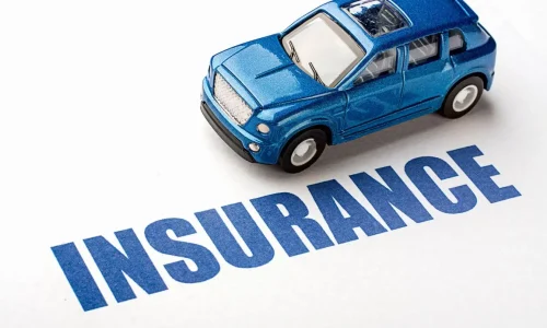 Voiture miniature bleue posée sur le mot Insurance, image illustrant la question du coût d’un conducteur secondaire sur une assurance auto