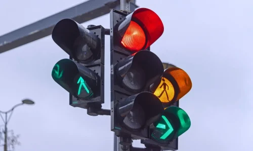 Feu rouge allumé avec signaux verts et piétons illustrant le risque d’amende et perte de points en cas de non-respect.