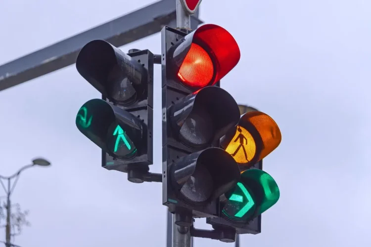 Feu rouge allumé avec signaux verts et piétons illustrant le risque d’amende et perte de points en cas de non-respect.