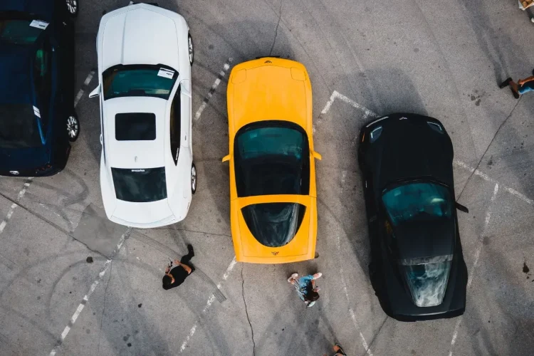 Vue aérienne de voitures garées avec personnes en mouvement, image illustrant le délit de fuite en stationnement et les sanctions prévues par la loi.