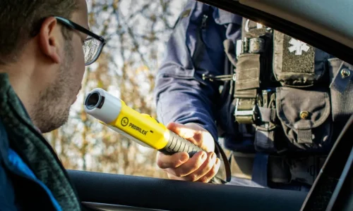 Policier en uniforme tenant éthylotest vers conducteur, image illustrant un contrôle de police et l’importance de connaître ses droits.