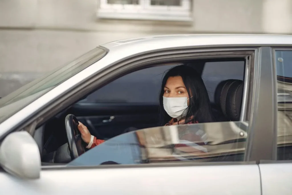 Conducteur masqué assis dans une voiture, image évoquant la vérification médicale obligatoire pour obtenir un certificat lié au permis de conduire.