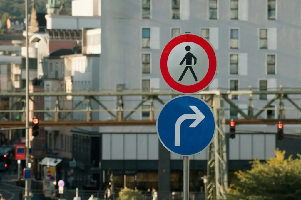 Panneaux urbains indiquant interdiction piétonne et flèche, image illustrant la règle de priorité à droite dans la circulation.