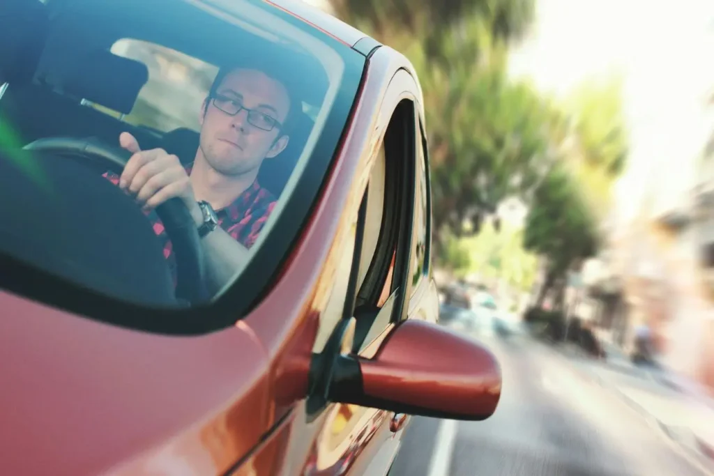 Conducteur en chemise rouge tenant volant, image illustrant la nécessité d’un permis de conduire international pour circuler à l’étranger.