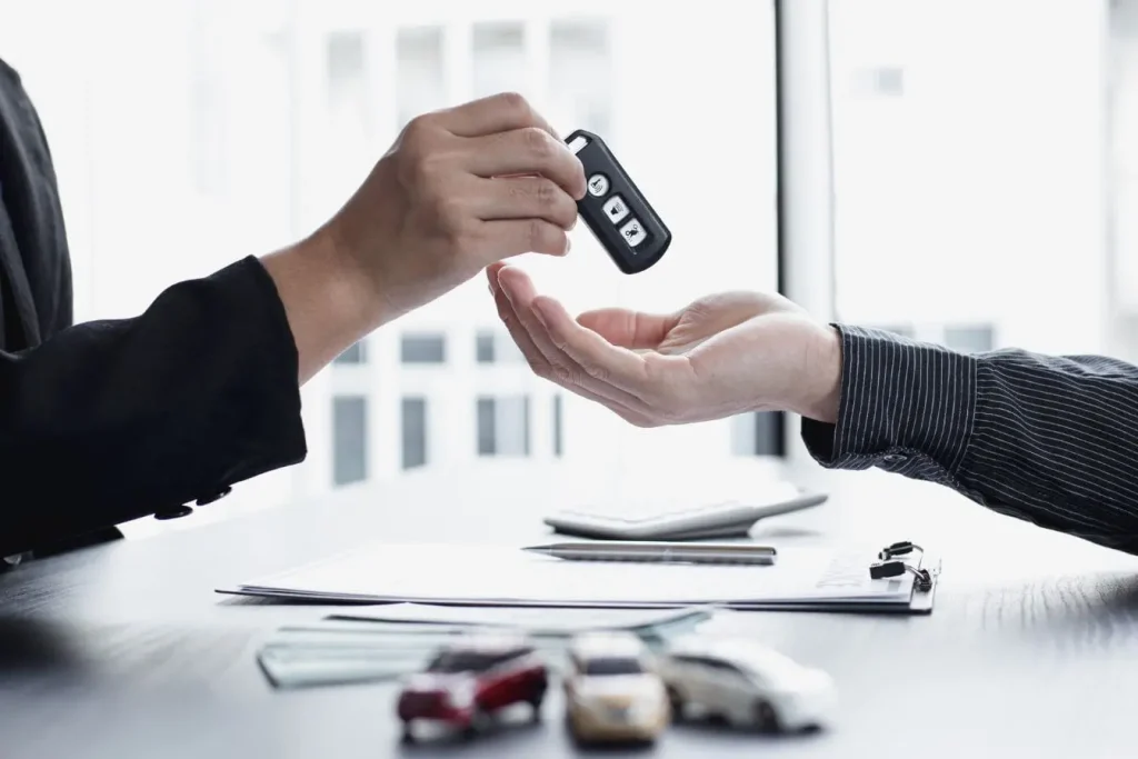 Main tendant une clé de voiture à une autre personne, image illustrant la protection complète d’une assurance auto tous risques.