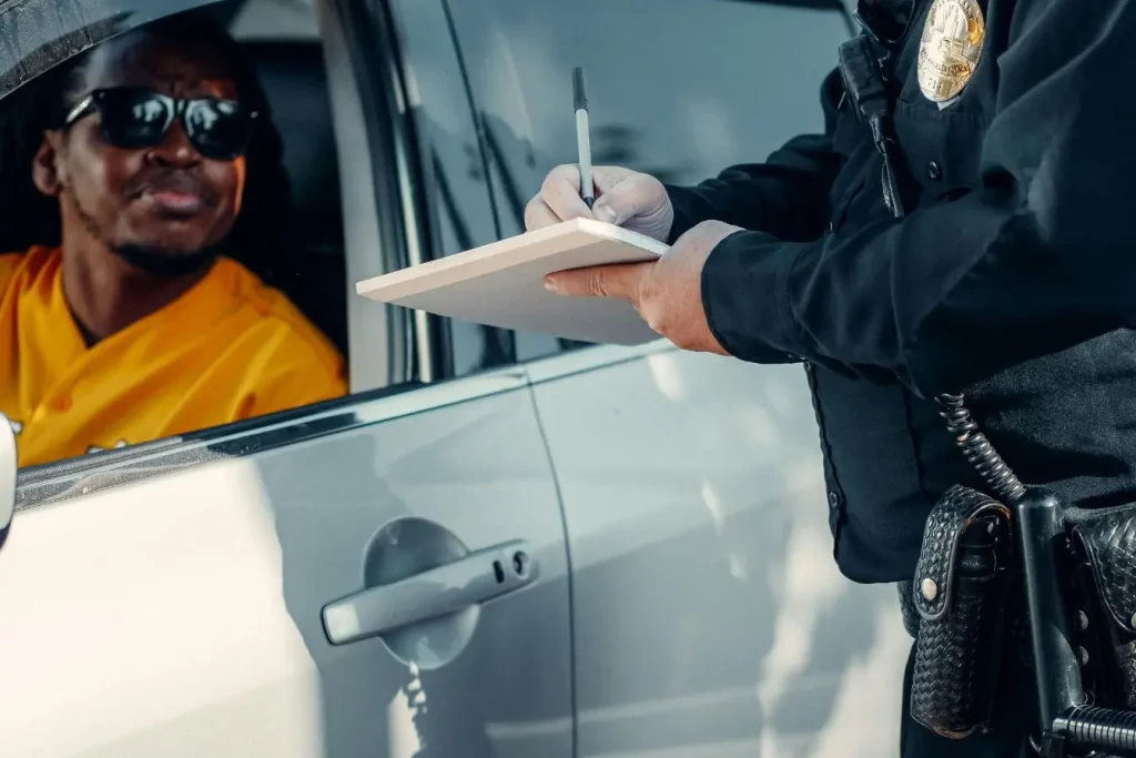 Conducteur en lunettes face à agent, symbole du contrôle de police et des règles à respecter pour bien se comporter.