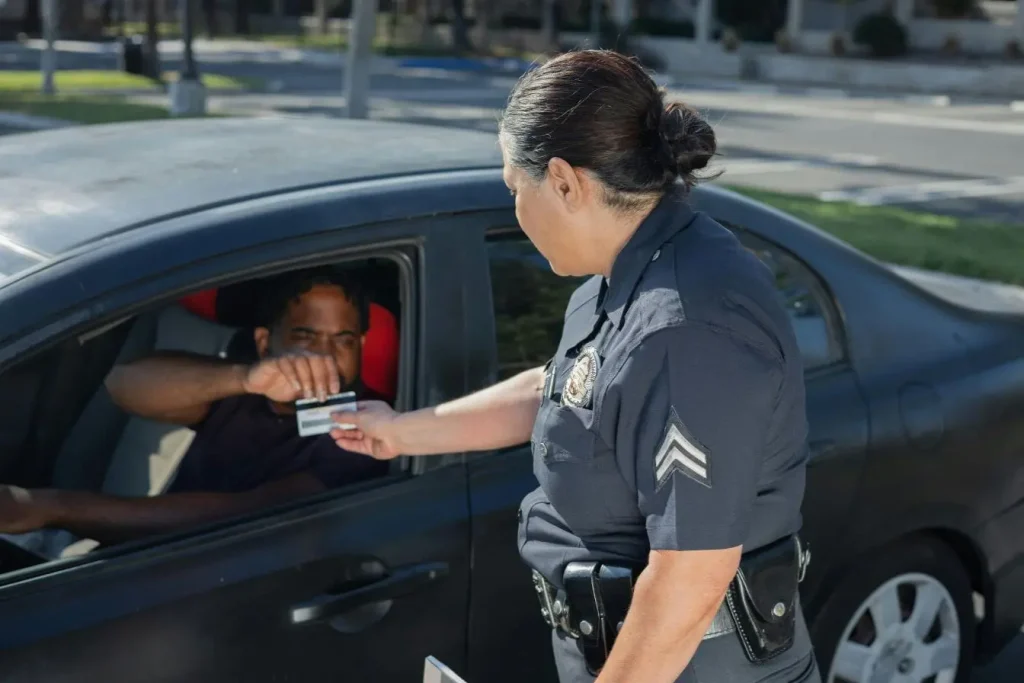 Policier en uniforme recevant un document d’un conducteur, scène évoquant les conséquences d’une utilisation du téléphone au volant lors d’un contrôle routier.