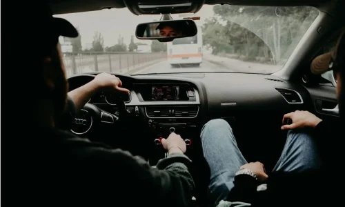 Vue intérieure d’une voiture avec conducteur et passager, image illustrant le calcul du coût réel d’un trajet en voiture.