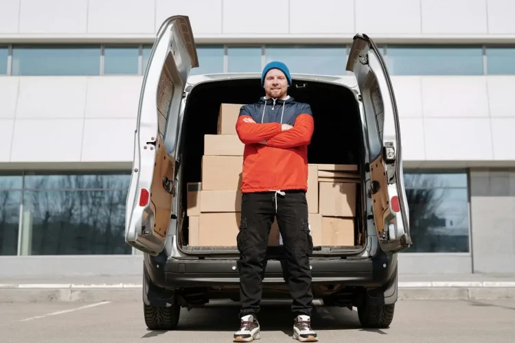 Employé devant un utilitaire d’entreprise chargé de colis illustrant l’usage d’une voiture de société considérée comme avantage en nature dans le cadre professionnel.