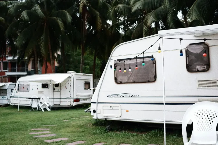 Caravane blanche décorée de guirlandes colorées sur terrain herbeux, image illustrant la nécessité d’un permis adapté pour tracter une caravane.