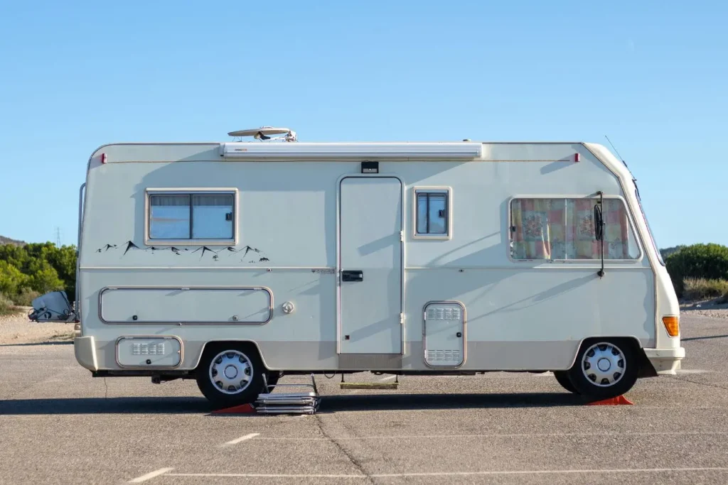 Camping-car stationné sur terrain avec collines, image illustrant la nécessité d’un permis adapté pour tracter une caravane en toute sécurité.