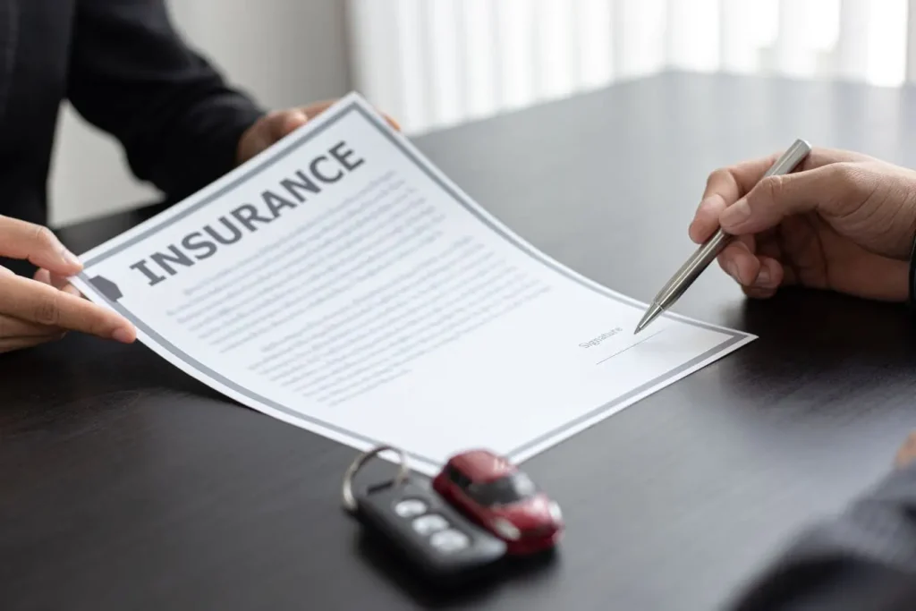 Personnes assises à table avec contrat d’assurance reflétant la vigilance nécessaire pour comprendre franchise absolue et relative en assurance auto.