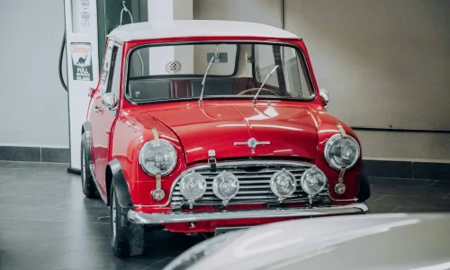 Voiture compacte vintage aux phares ronds chromés, symbole des pratiques liées aux véhicules de collection.