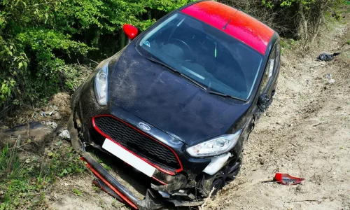 Véhicule endommagé dans fossé observé par expert chargé d’estimer coûts et causes de l’accident.