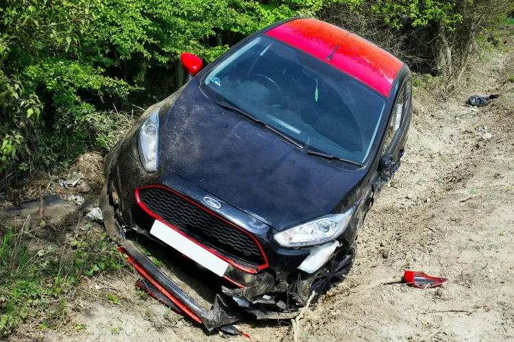 Véhicule endommagé dans fossé observé par expert chargé d’estimer coûts et causes de l’accident.