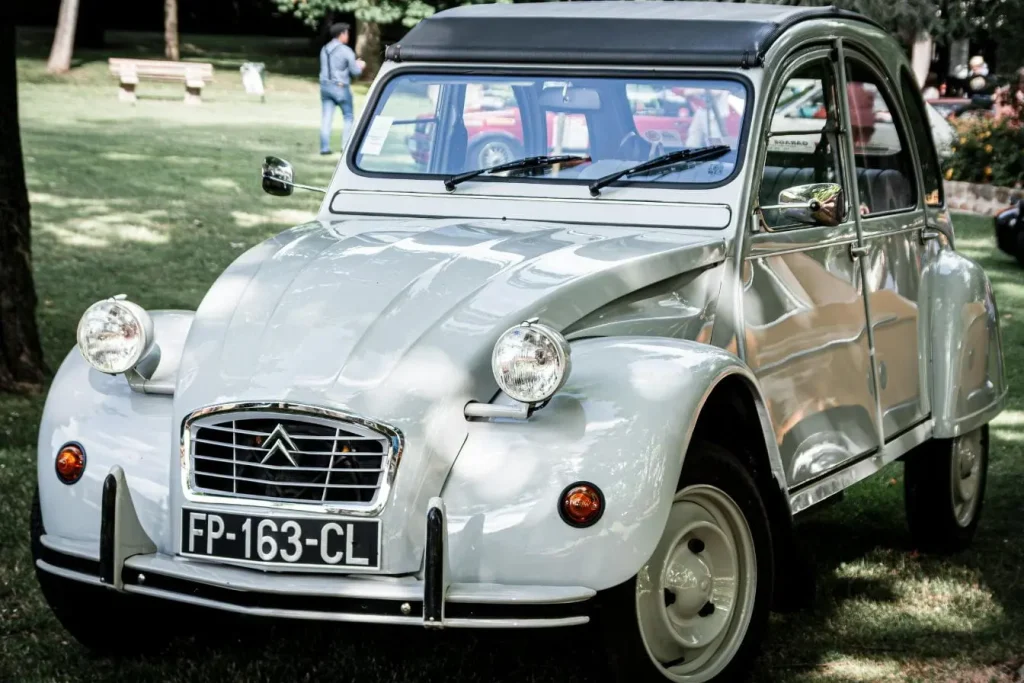 Citroën 2CV argentée garée sur pelouse, image illustrant un véhicule de collection.