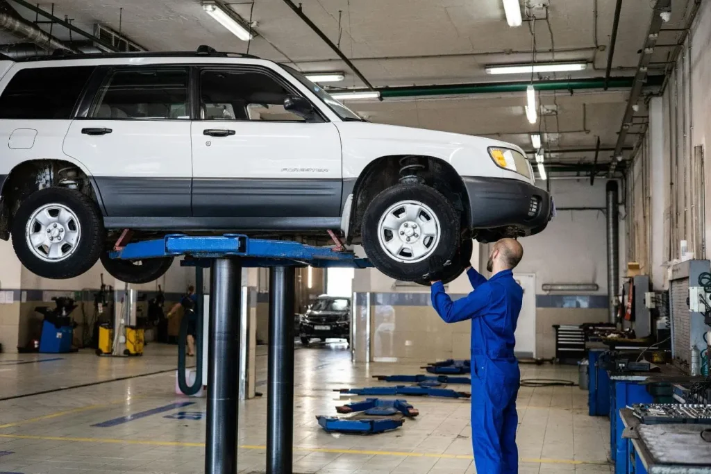 SUV blanc levé sur pont hydraulique dans atelier, image illustrant un véhicule éligible au contrôle technique.