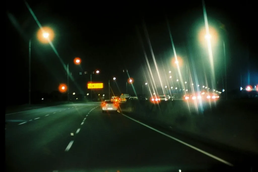 Scène nocturne avec feux rouges de véhicules reflétant l’importance de garder ses distances selon les règles de conduite sur autoroute.