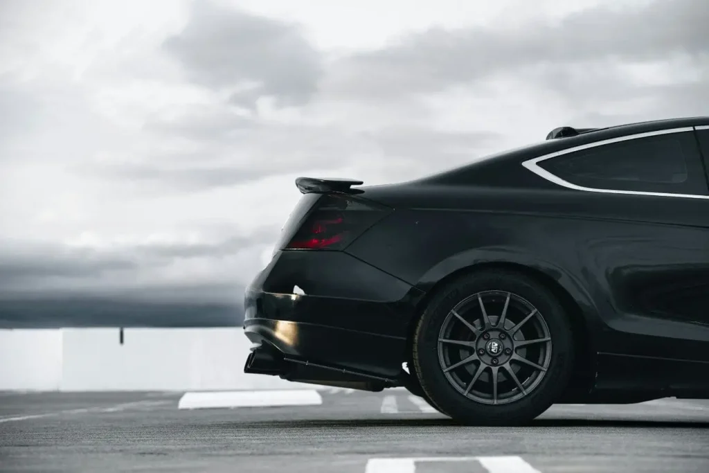 Vue arrière d’un véhicule noir brillant avec spoiler, image illustrant l’amélioration de la tenue de route par ses équipements de performance.