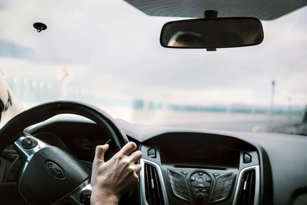 Main tenant le volant d’une voiture sur autoroute reflétant l’importance de respecter les règles de conduite et la vigilance en circulation rapide.