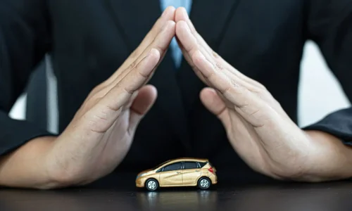 Mains formant triangle au-dessus d’une voiture dorée reflétant la protection offerte par l’assurance auto et ses franchises absolue et relative.