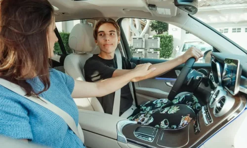 Deux jeunes assis à l’avant d’une voiture moderne, ceinture attachée, illustrant la question de l’âge minimum pour conduire sans permis.