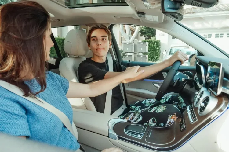 Deux jeunes assis à l’avant d’une voiture moderne, ceinture attachée, illustrant la question de l’âge minimum pour conduire sans permis.