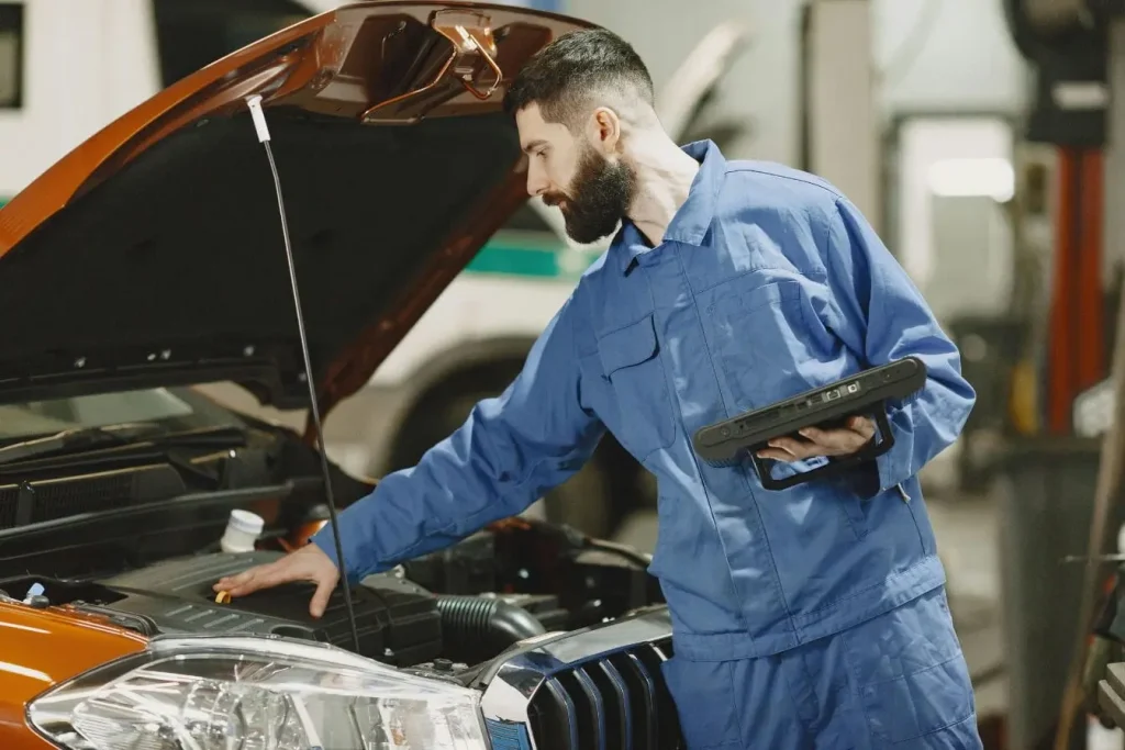 Technicien tenant appareil numérique devant moteur orange, symbole du diagnostic OBD et de la lecture des codes défaut.