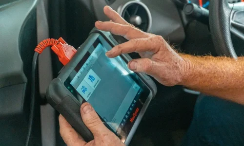 Conducteur utilisant un scanner automobile relié au véhicule, image illustrant le diagnostic OBD et la lecture des codes d’erreur moteur.