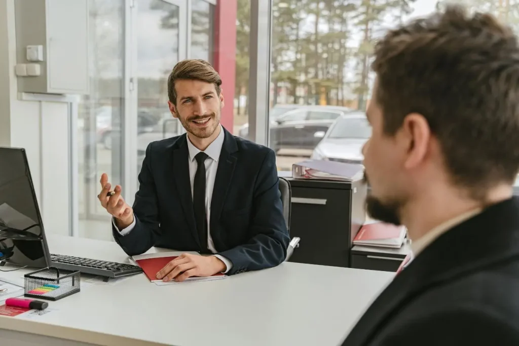 Deux personnes en tenue formelle discutant à un bureau, image illustrant la signature d’un contrat d’assurance auto.