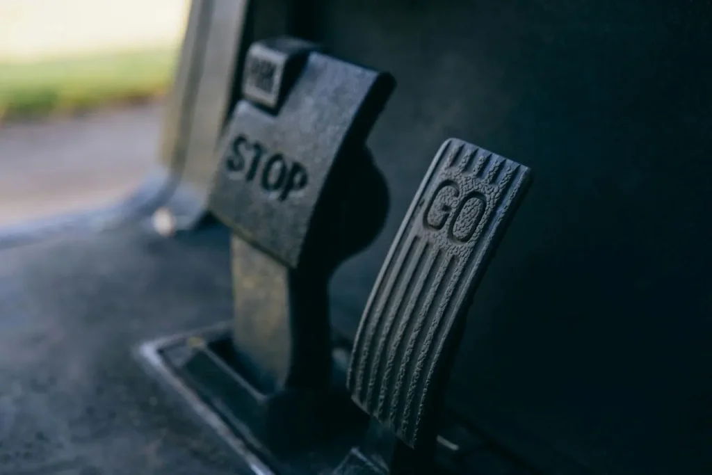 Pédales métalliques STOP et GO sur sol de véhicule, image représentant l’amélioration de la tenue de route par un contrôle clair et réactif.