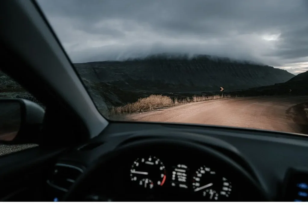 Vue depuis voiture sur route sinueuse brumeuse, image illustrant la conduite par temps de brouillard et l’importance des règles de sécurité.