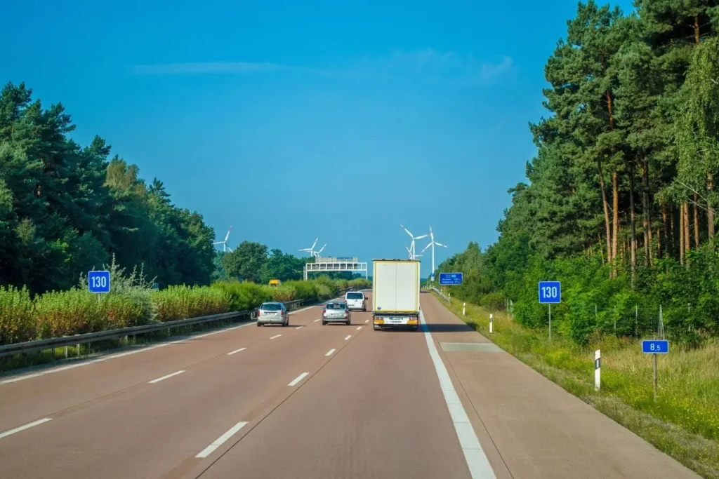 Scène d’autoroute bordée d’arbres avec voitures et camion, image qui illustre le contexte où radars pédagogiques et radars fixes se distinguent.