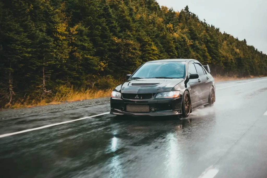 Voiture sportive avançant sur route humide reflétant la distinction entre moteur atmosphérique fluide et turbocompressé puissant.