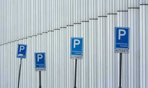 Série de panneaux bleus alignés devant mur métallique, image qui illustre le fonctionnement de la zone bleue et l’usage du disque de stationnement.