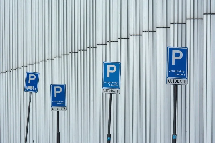 Série de panneaux bleus alignés devant mur métallique, image qui illustre le fonctionnement de la zone bleue et l’usage du disque de stationnement.