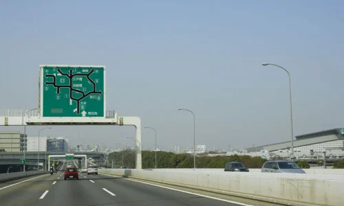 Panneau vert complexe au-dessus d’une autoroute avec véhicules en mouvement, image qui illustre la signalisation temporaire et la sécurité routière.
