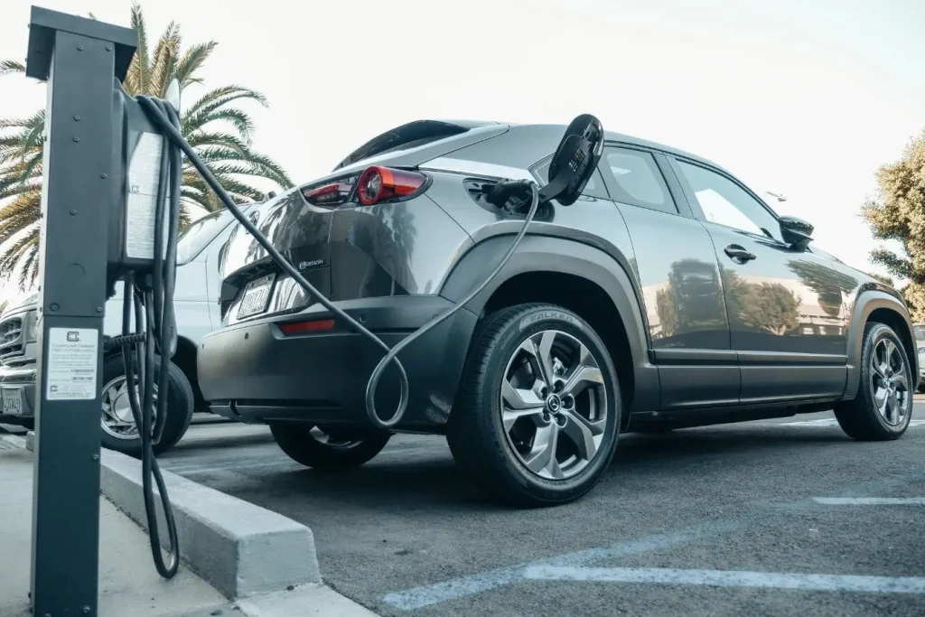 Voiture grise branchée à borne publique sur parking, image qui illustre l’entretien particulier d’une hybride rechargeable.