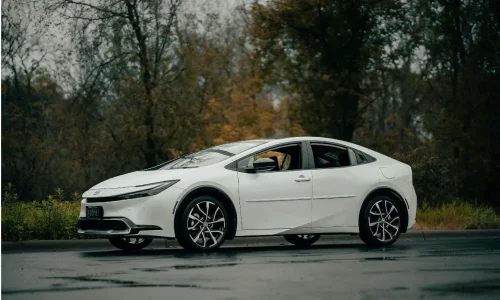 Voiture élégante aux phares affûtés posée sur sol mouillé, reflet des besoins spécifiques d’entretien d’une hybride rechargeable.