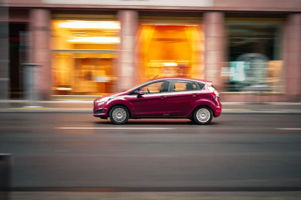 Véhicule rouge capturé en pleine vitesse, image qui traduit la performance du freinage régénératif.