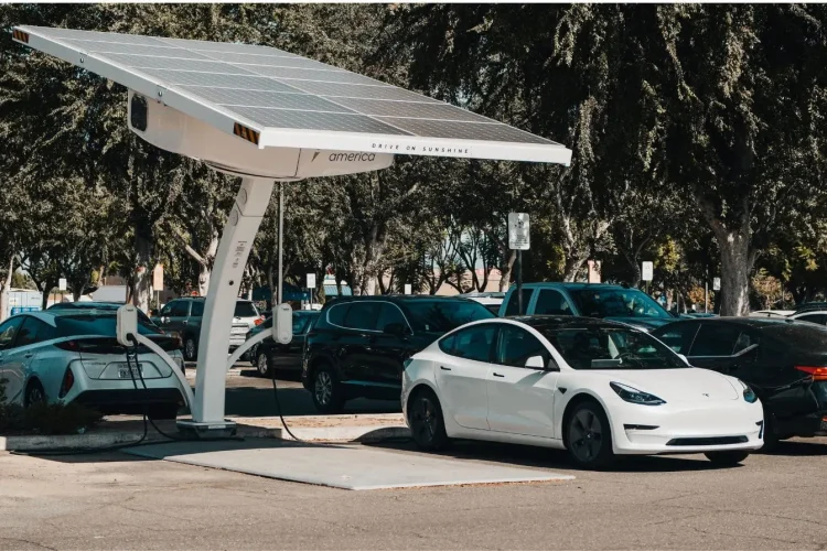 Voiture électrique branchée sous panneaux solaires, reflet des enjeux de la recharge rapide DC et de la longévité des batteries.