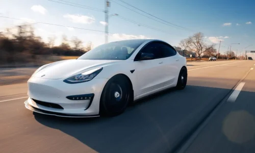 Voiture électrique blanche roulant sur route ensoleillée, reflet d’un véhicule qui démarre mais peut caler, évoquant causes et solutions mécaniques.